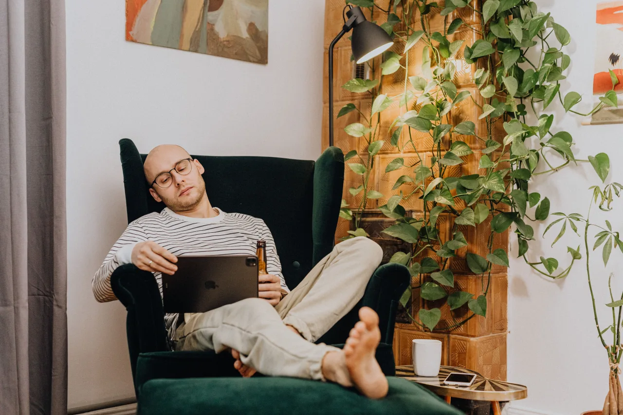 Person relaxing in an armchair with a tablet at home